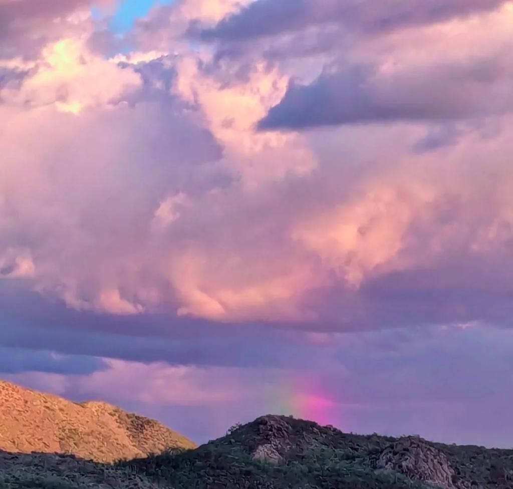 Dramatic purple sunset sky with rainbow over the mountains